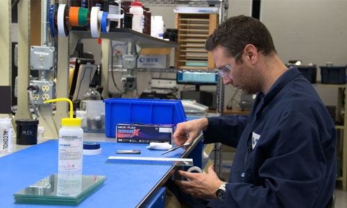 An application engineer prepares substrate surfaces in order to perform adhesive bonding tests.